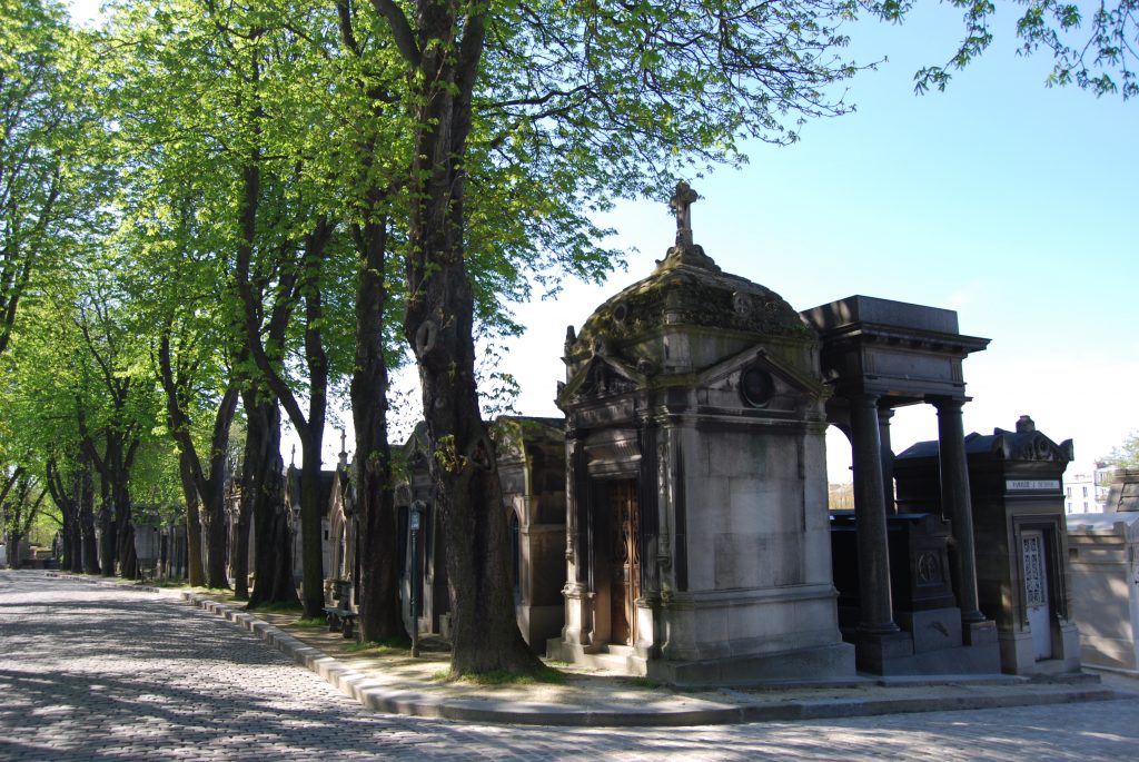 Grabmäler an einer Allee auf dem Friedhof bei Sonnenschein